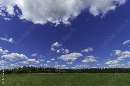 Rustic summer landscape. Fields and beautiful white clouds on a blue sky