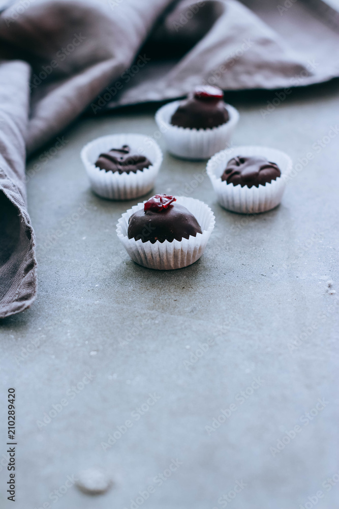 Healthy raw energy chocolate candy with cocoa, coconut, sesame, chia, cranberries and icing. Vegan chocolate truffles on a gray background. Copy space. Healthy raw energy chocolate candy with cocoa, coconut, sesame, chia, cranberries and icing. Vegan chocolate truffles on a gray background. Copy space.