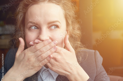 Woman giggles covering her mouth with hand photo