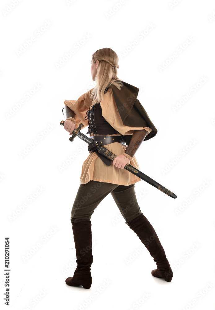 full length portrait of girl wearing medieval costume with sword. standing pose with back to the camera, isolated on white studio background. full length portrait of girl wearing medieval costume with sword. standing pose with back to the camera, isolated on white studio background.