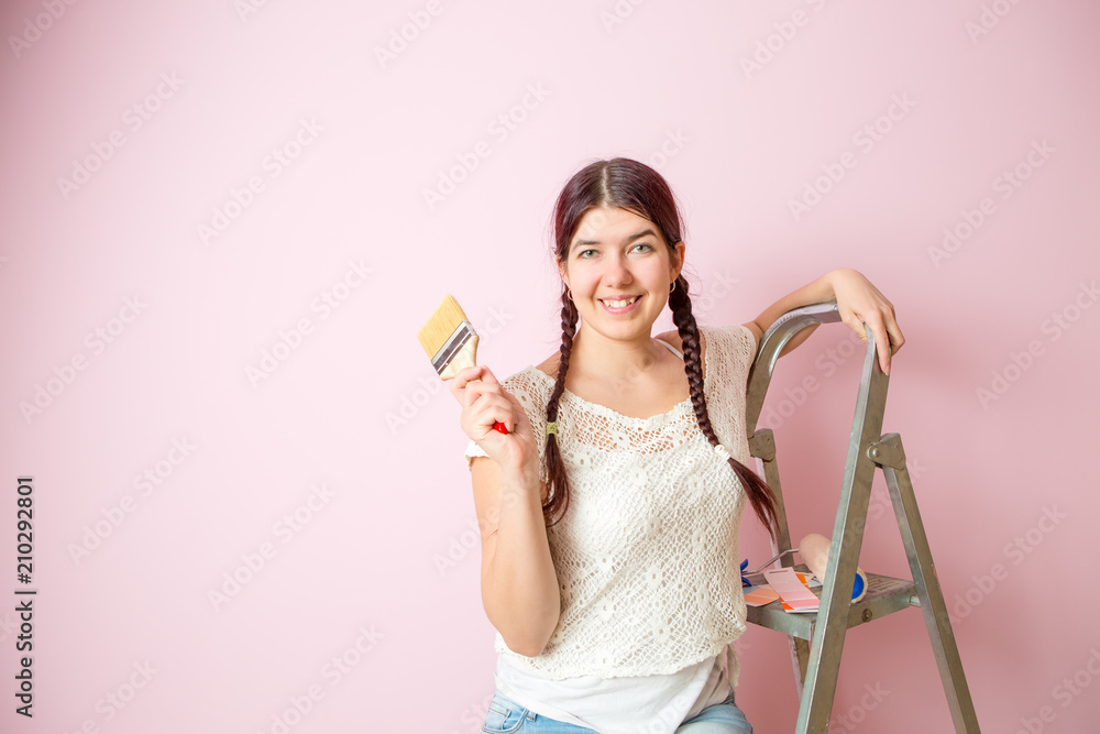 Picture of cheerful woman with brush next to stepladder and roller against blank pink wall Picture of cheerful woman with brush next to stepladder and roller against blank pink wall