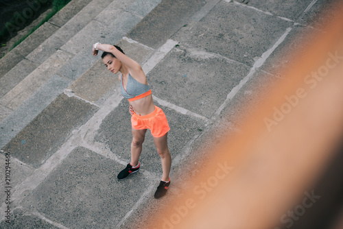 overhead view of young sportswoman stretching and exercising in city