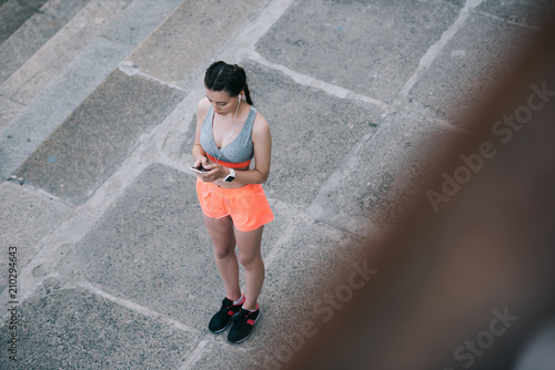 overhead view of young sportswoman using smartphone