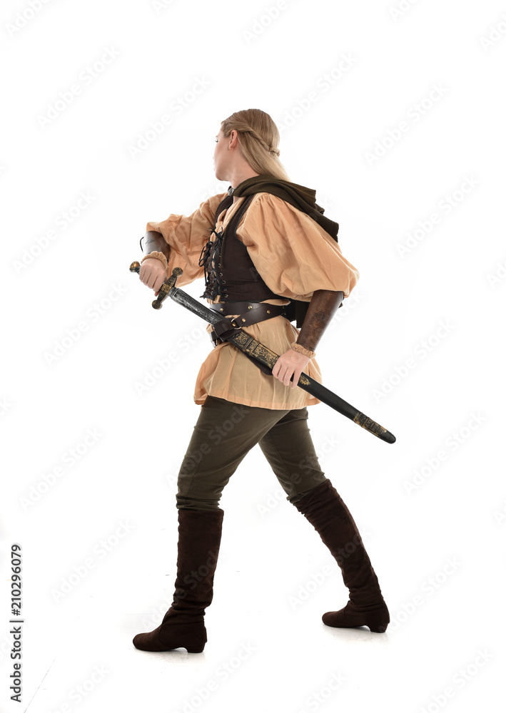 full length portrait of girl wearing medieval costume with sword. standing pose with back to the camera, isolated on white studio background. full length portrait of girl wearing medieval costume with sword. standing pose with back to the camera, isolated on white studio background.