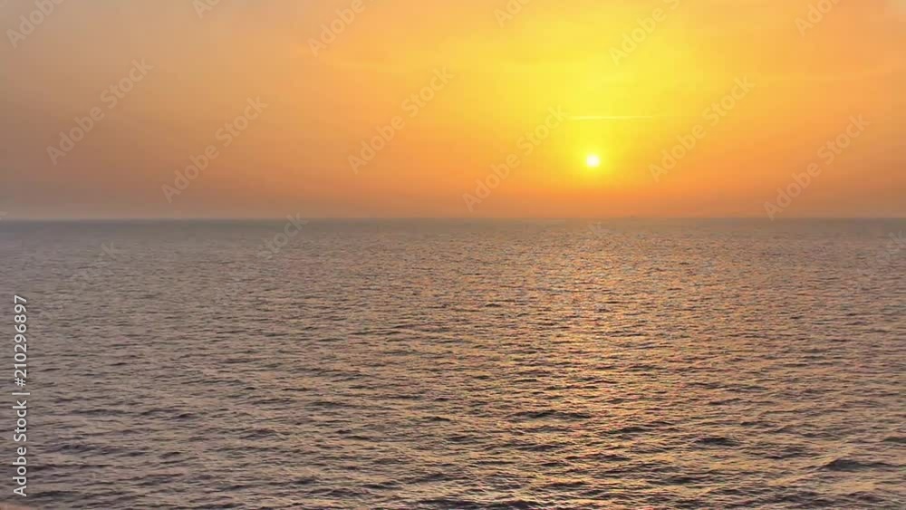 a spectacular sunset on the sea seen from a boat in navigation /the sunset paints the orange and yellow sky and reflects the colors on the sea a spectacular sunset on the sea seen from a boat in navigation /the sunset paints the orange and yellow sky and reflects the colors on the sea