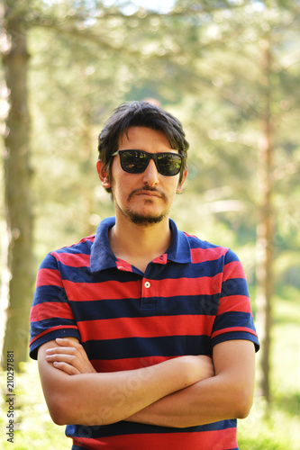 Young man's outdoors portrait looking at the camera with natural green background. Neutral, happy, sad, disgust, fear, surprise and angry Facial Emotions.