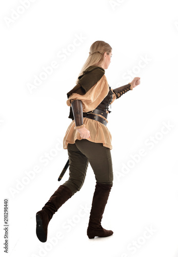 full length portrait of girl wearing medieval costume with sword. standing pose with back to the camera, isolated on white studio background.