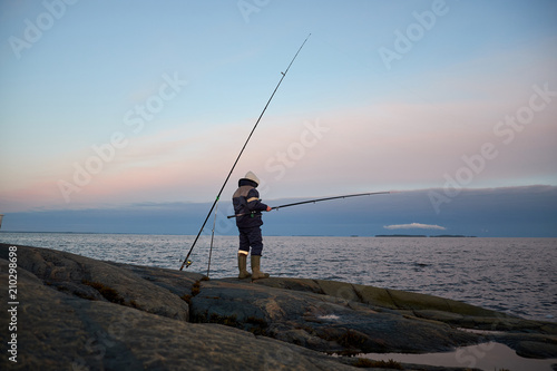 the fisherman stands on a rocky shore