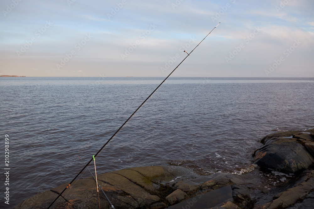 the fishing pole is on a rocky shore