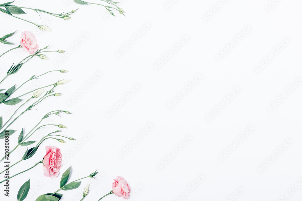 Floral flat lay frame of pink flowers on white background
