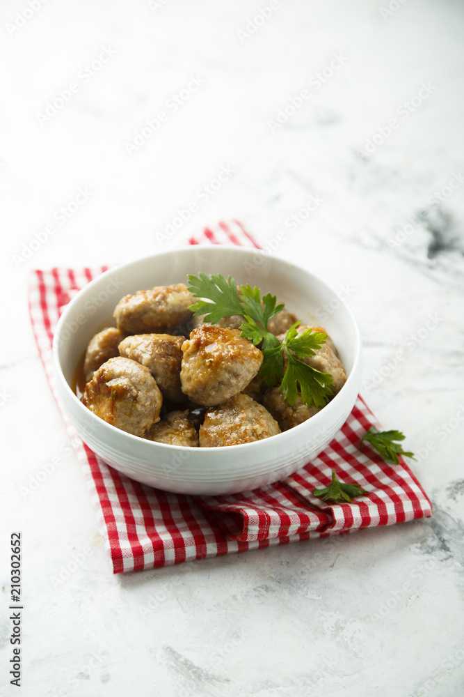 Homemade meatballs with fresh parsley in a white bowl