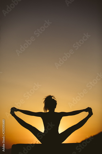 Young woman is practicing yoga on the mountain at sunset. Silhouette of young woman practicing yoga outdoor.