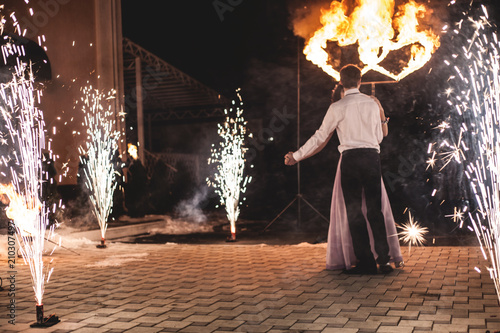 Canvastavla Young groom and bride with two burning hearts fireshow at night, wedding or marriage concept