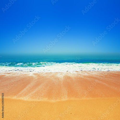 Beautiful Tropical beach with Soft wave of blue ocean, golden sand and sky. Summer travel holiday background concept. Sea panorama with copyspace.