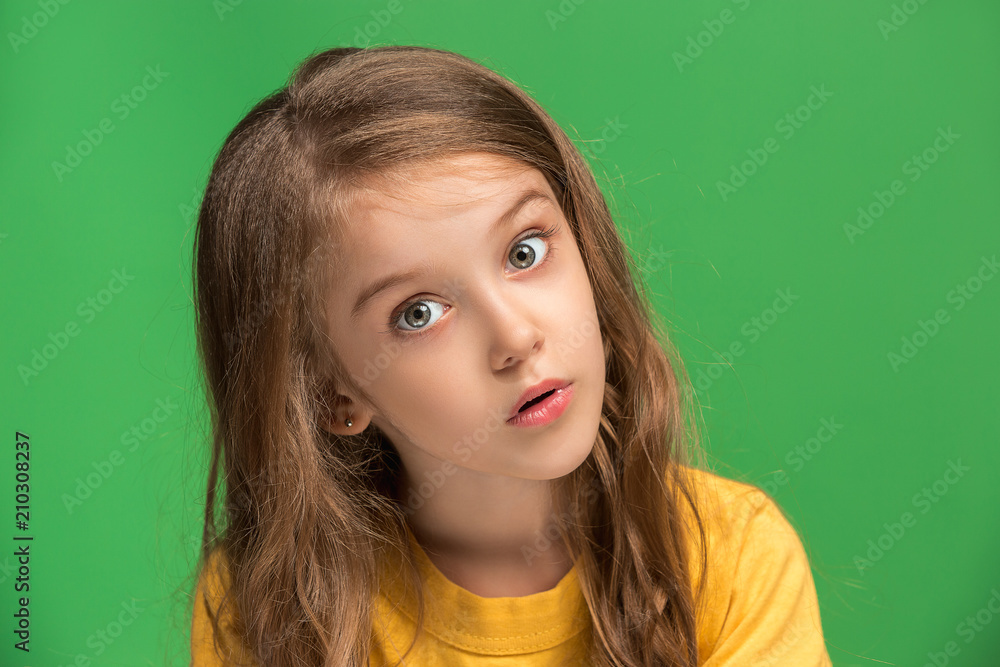 Fototapeta premium Beautiful teen girl looking suprised isolated on green