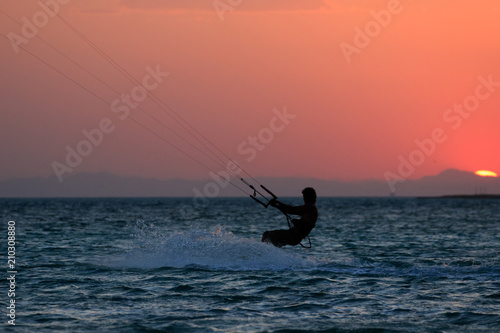 Kiteboarder sportsman under sunset sun, freestyle kiteboarding rider on the evening kitesession, sunset in the sea, extreme watersports, active lifestyle, recreation hobby and fun time