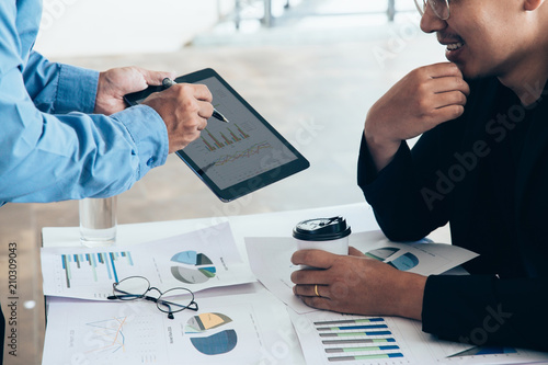 Asian businessmen convened for a meeting with  digital graphs and charts describing their work.