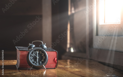 Close up holy bible and alarm clock on wood table.