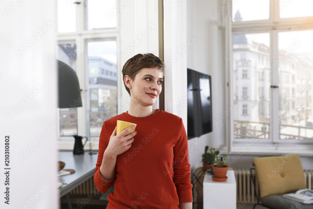 Woman standing in her comfortable home, drinking coffee Woman standing in her comfortable home, drinking coffee