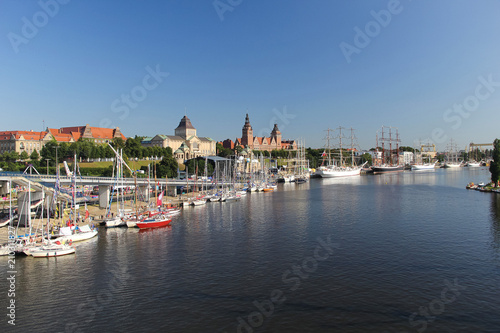 City view of town Szczecin, west Poland, with river banks and tall sail ships on the port.