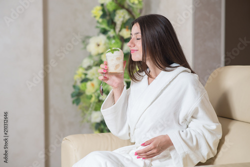 Happy woman in bathrobe sitting and holding an oxygen foam cocktail in SPA center