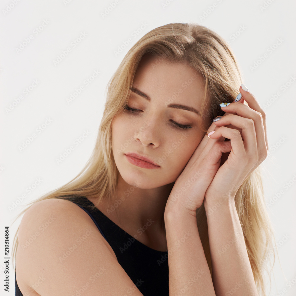 Young beautiful sexy woman in blue jeans shorts and black shirt posing and sitting on simple black chait in white studio. Fashion model with long straight hair and closed eyes.