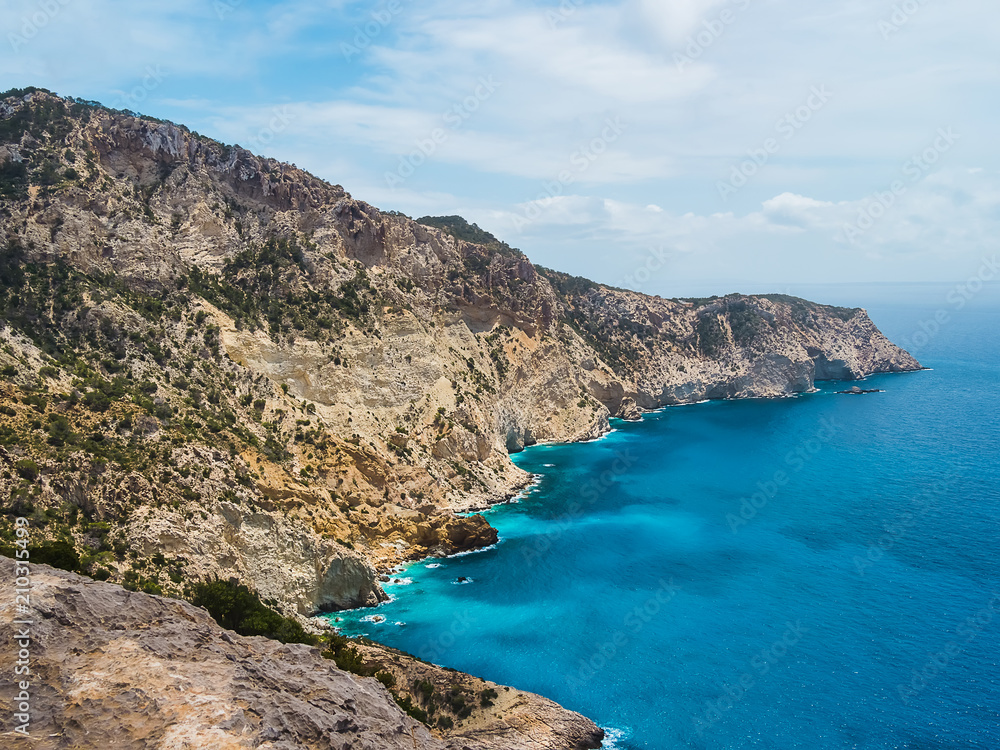 Acantilados, mar mediterraneo turquesa y montañas, del parque natural de Cala D´hort, en Ibiza, España. Es una ruta de trekking que lleva hasta la Torre des savinar para poder contemplar Es Vedrá.