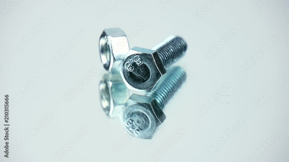 Metal bolt turning together with nut on mirror background. Closeup Metal bolt turning together with nut on mirror background. Closeup
