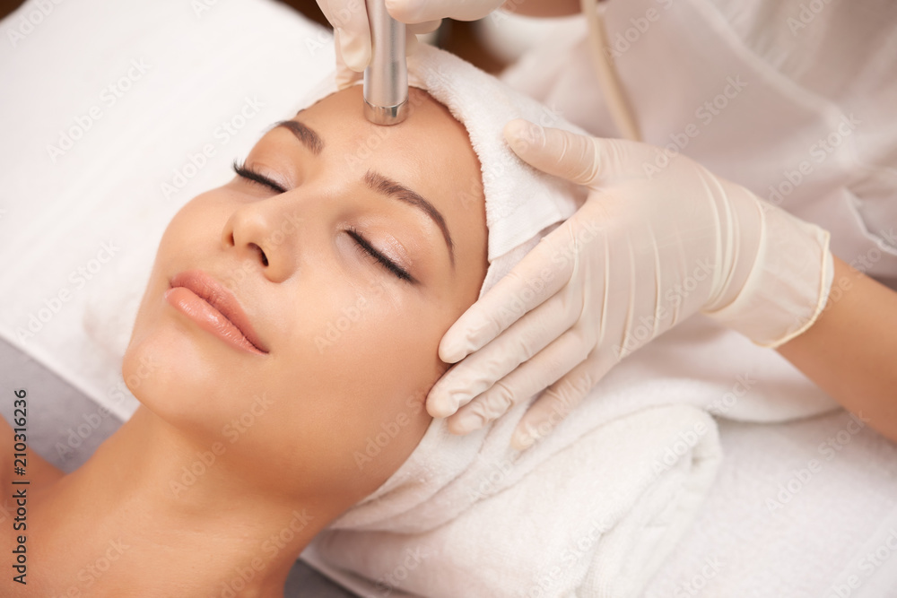 Young relaxed female having anti-wrinkle beauty procedure on face