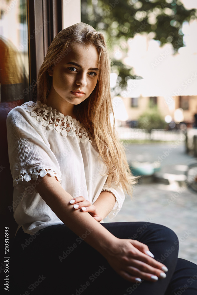 young girl in coffeeshop sitting on the window sill young girl in coffeeshop sitting on the window sill