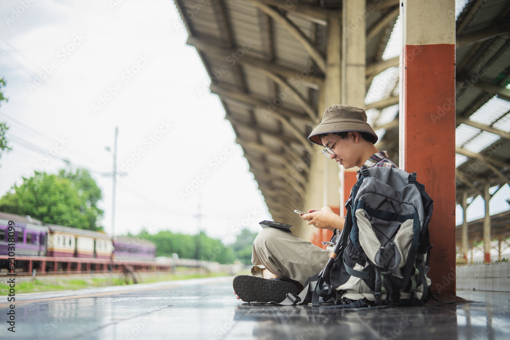 Traveler man sitting and waits train on railway platform