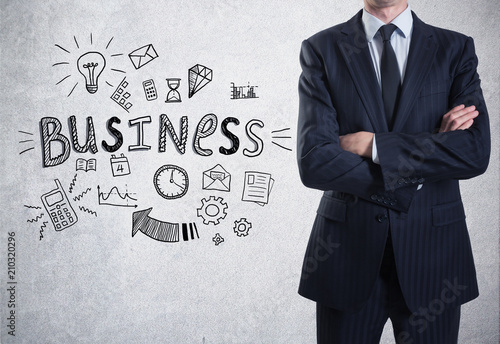 A man dressed in a suit on a concrete wall background with a business sketch on it