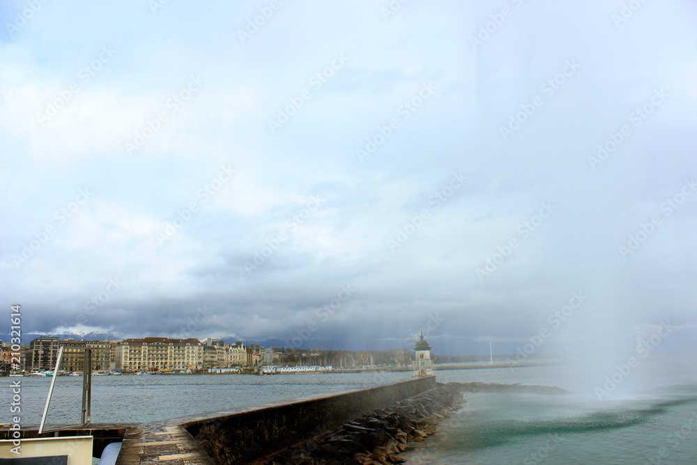Swiss famous view in Geneva with popular fountain, lake and lighthouse on rainy spring day Swiss famous view in Geneva with popular fountain, lake and lighthouse on rainy spring day