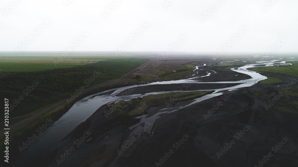 aerial view of river in black sand with many junctions