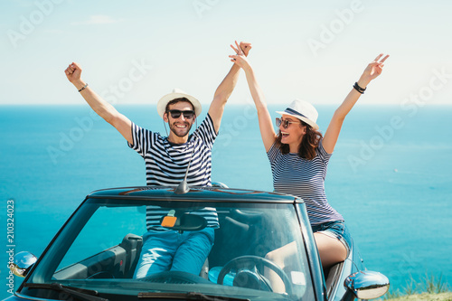 Young attractive couple posing in a convertible car, by the sea © Mediteraneo
