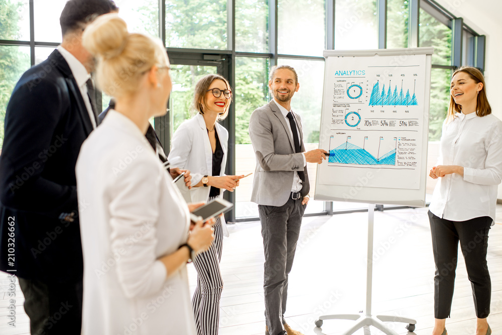A group of business people standing together during the conference with flip chart at the modern office A group of business people standing together during the conference with flip chart at the modern office