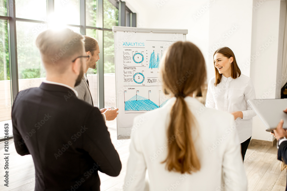A group of business people standing together during the conference with flip chart at the modern office