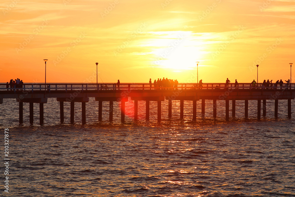 Sea bridge with people at sunset. Baltic sea beach bridge in Palanga.