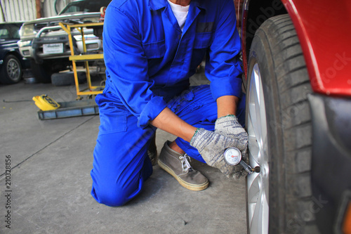 Car mechanic checking air pressure gauge for car in auto repair service