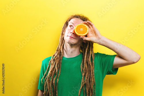 Wallpaper Mural Happy young man holding orange halves on a yellow background Torontodigital.ca