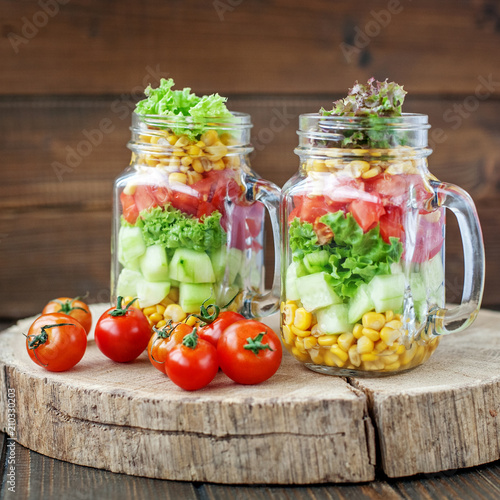 Two glass jars with vegetable salad and cherry tomatoes. Healthy