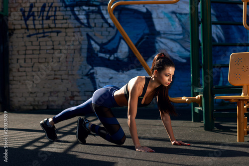 Fitness model exercising. Young beautidul tanned caucasian brunette doing exercises outdoors. healthy concept. Full length shot.