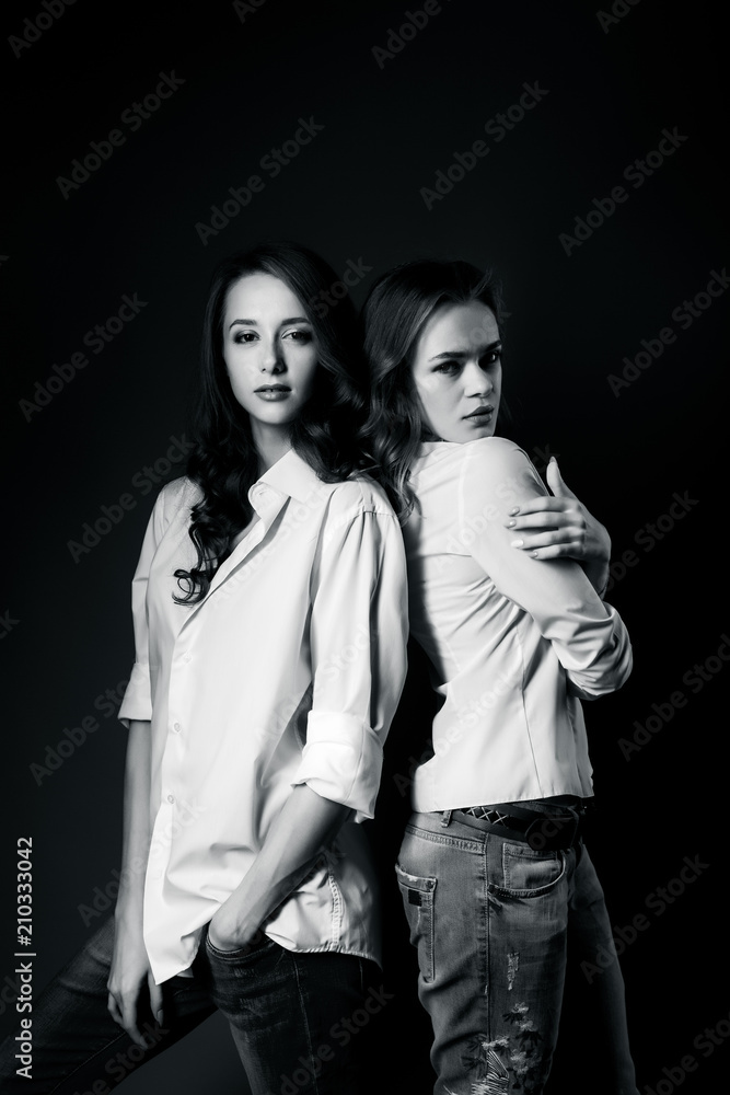 Two beautiful girls posing in white shirt and jeans