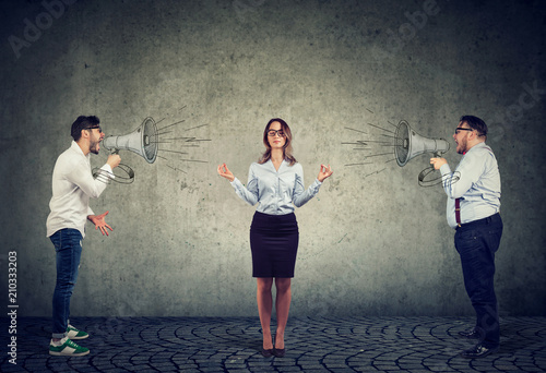 meditating business woman paying no attention to angry men screaming at her in megaphone