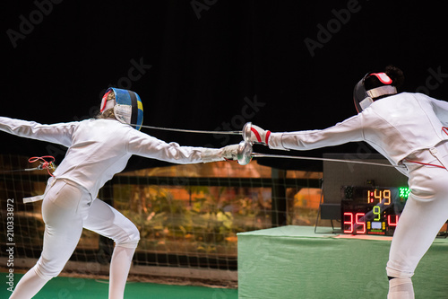 Two woman fencing athletes fight photo