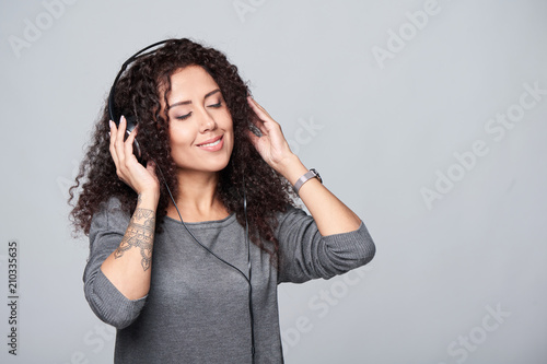 Woman listening enjoying music in headphones with closed eyes