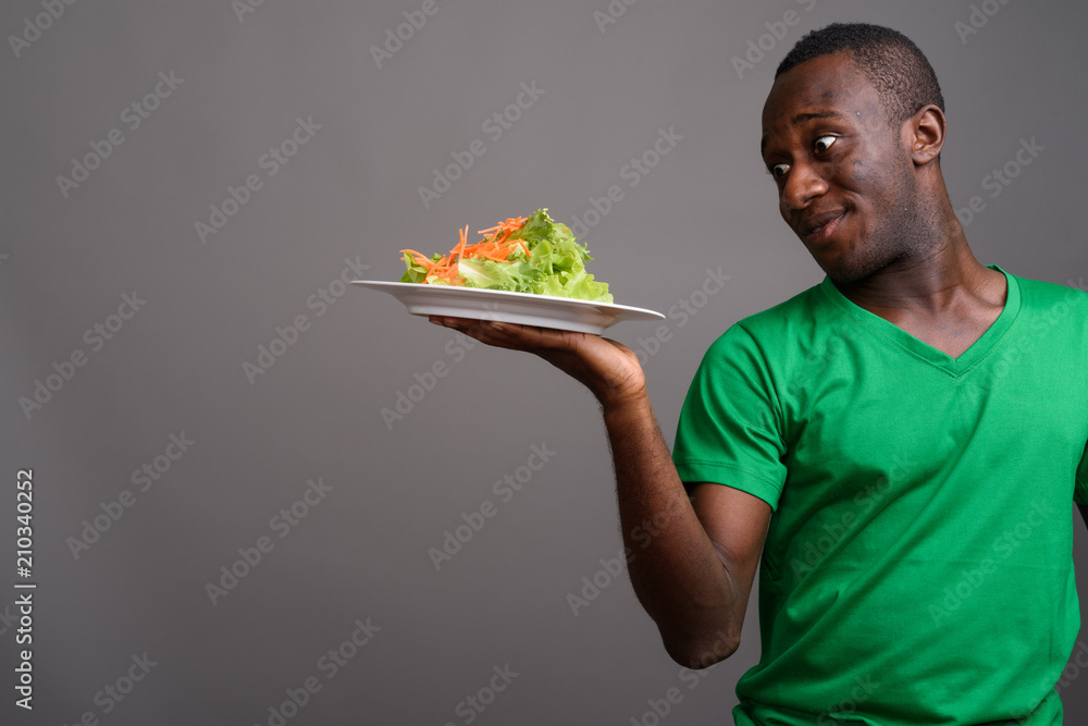 Young African man wearing green shirt against gray background Young African man wearing green shirt against gray background