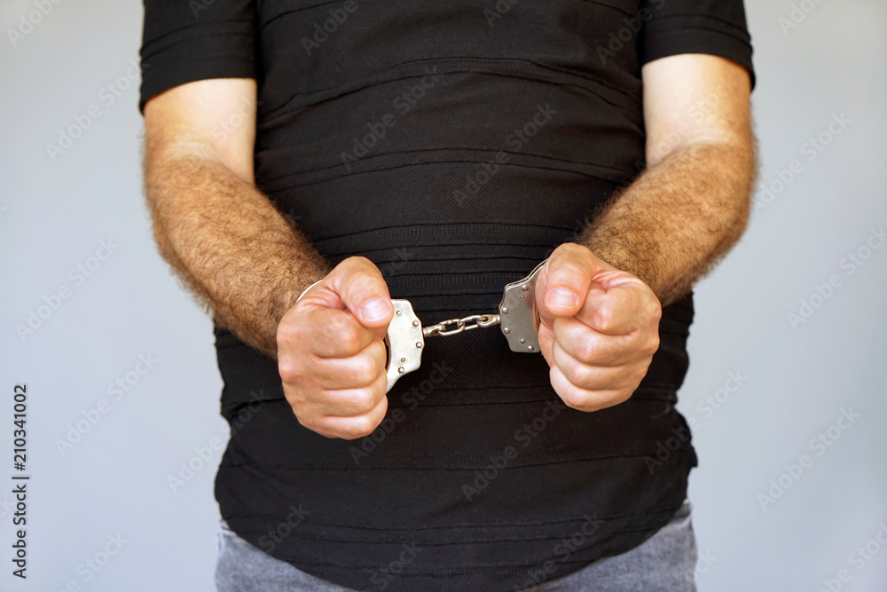 Obraz premium Close-up. Arrested man handcuffed hands. Prisoner or arrested terrorist, close-up of hands in handcuffs, selective focus.