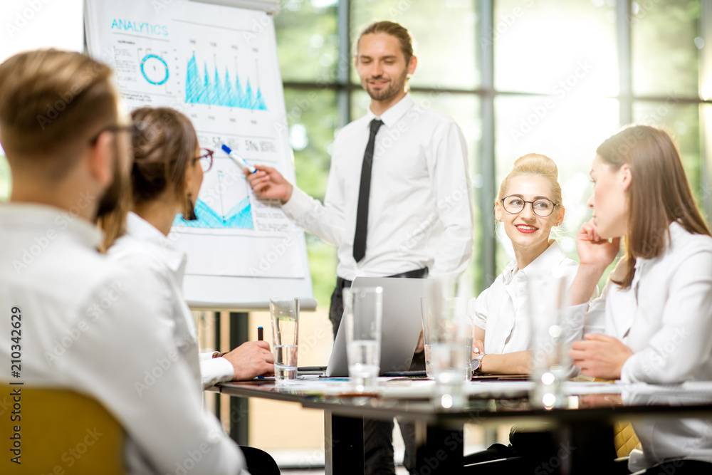 Handsome speaker reporting with flip chart during a business conference at the office on the green background Handsome speaker reporting with flip chart during a business conference at the office on the green background