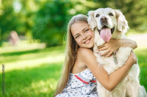 Little girl with golden retriever dog in the park